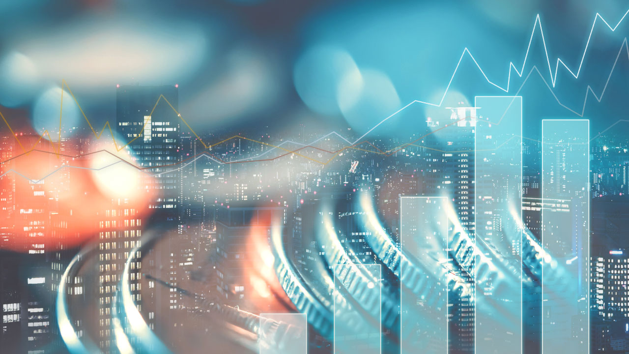 Finanziamenti, monete sfocate con in sottofondo palazzi e grafici